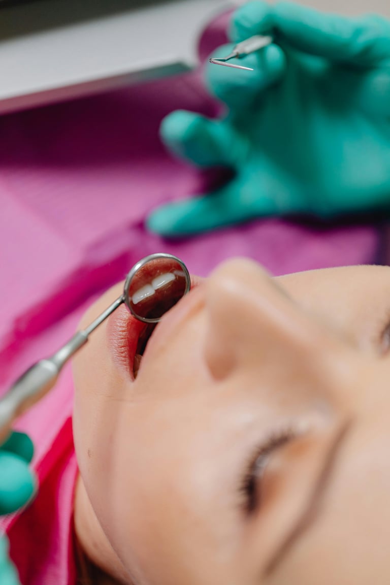 Dental professional in teal gloves examining a dental models teeth with mirror tools on pink background